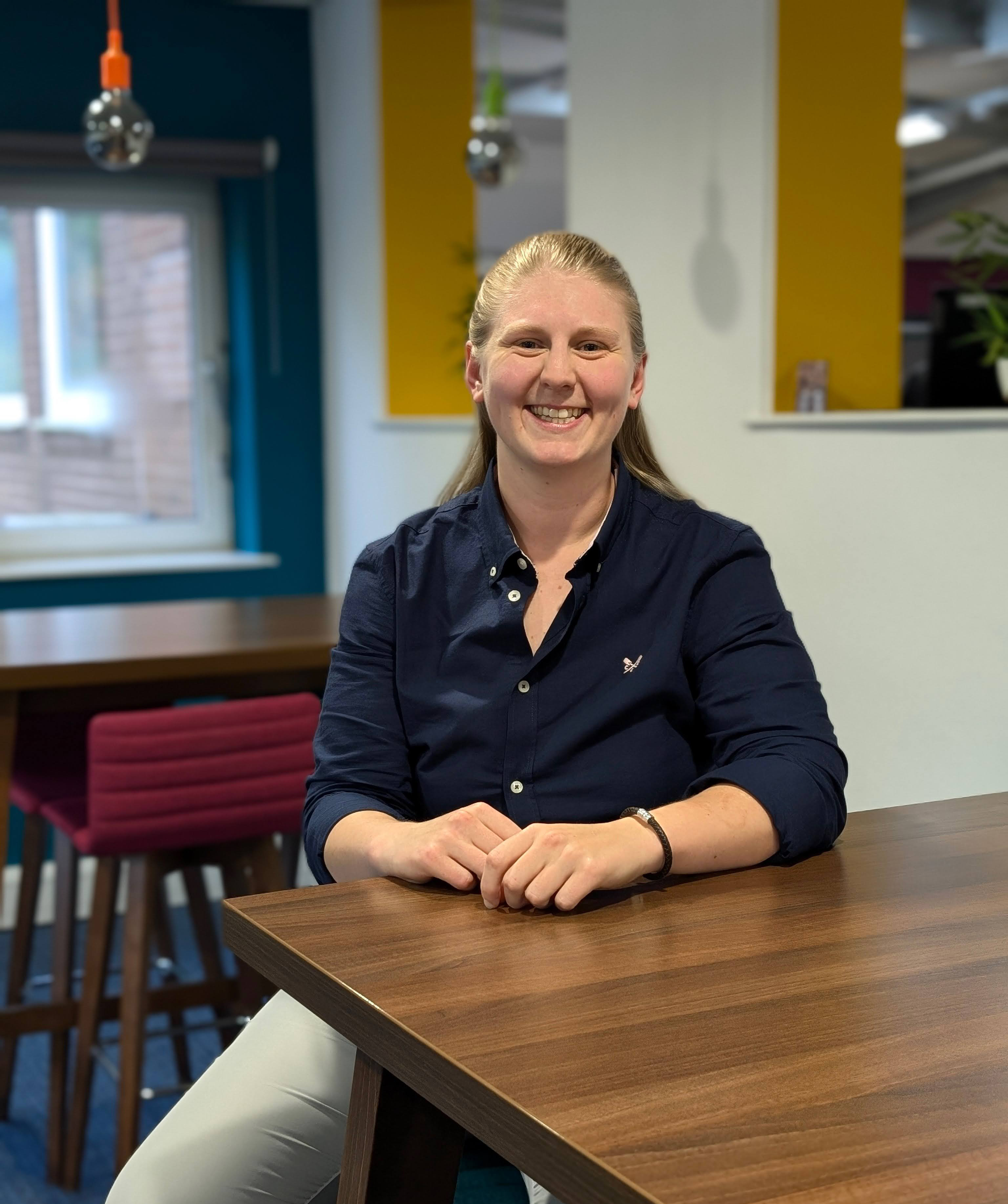 Sophie sitting at a desk in the office smiling.